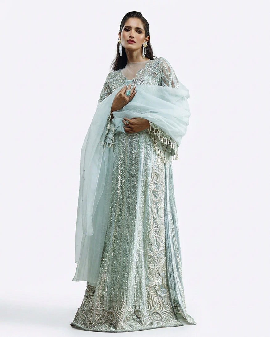 Woman wearing an Aqua embroidered Net suit with organza dupatta draped over one shoulder