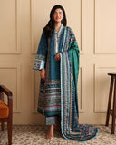Woman wearing blue printed raw silk suit standing against a panelled wall with green dupatta