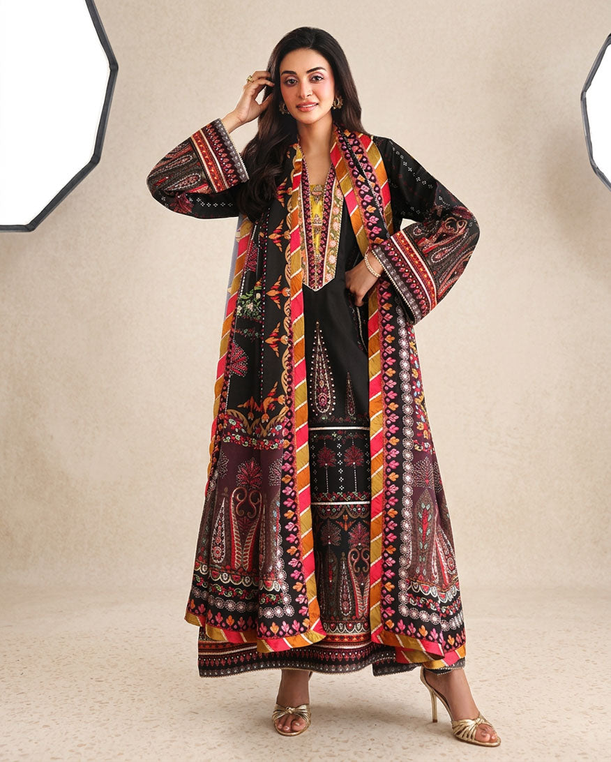 Woman wearing black printed raw silk suit with hand in hair against a studio backdrop