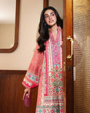 Woman wearing peach printed raw silk suit standing in doorway holding a clutch bag