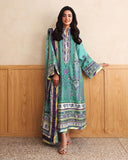 Woman wearing green printed raw silk suit leaning against a wood-panelled cabinet