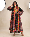 Woman wearing black printed raw silk suit with hand in hair against a studio backdrop
