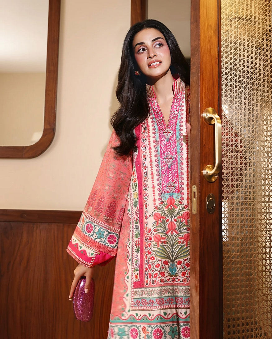 Woman wearing peach printed raw silk suit standing in doorway holding a clutch bag