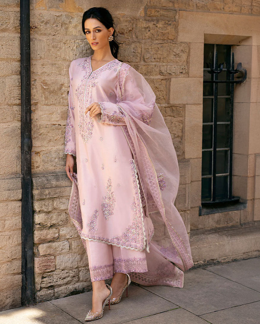 Woman in pink embroidered raw silk kurta with Swarovski crystal and tilla work, standing by stone window
