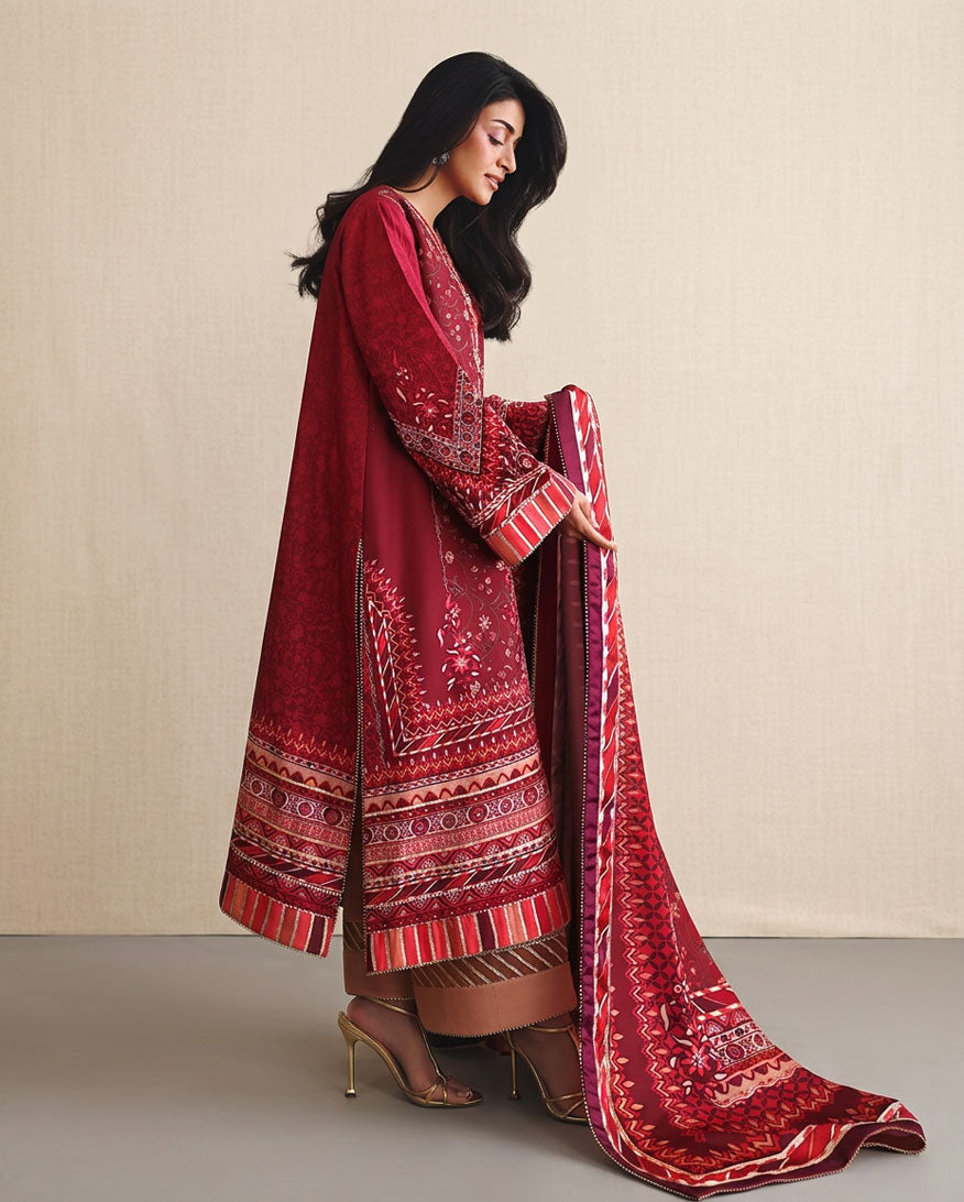 Side view of red printed raw silk suit with striped hem border, adjusting dupatta