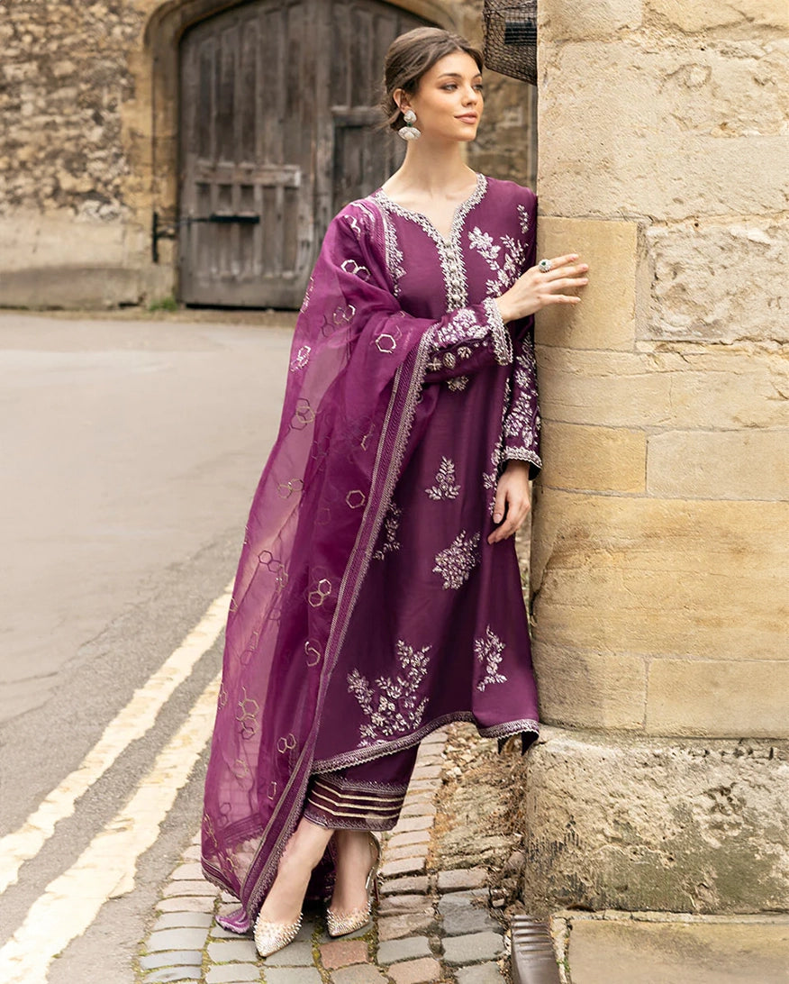 Woman wearing a Purple Raw Silk suit, glancing away beside a stone archway