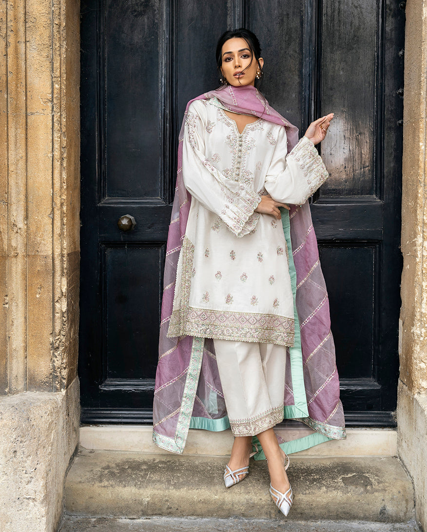 Woman wearing an Ivory resham-embroidered Raw Silk suit with a diagonal color-blocked dupatta