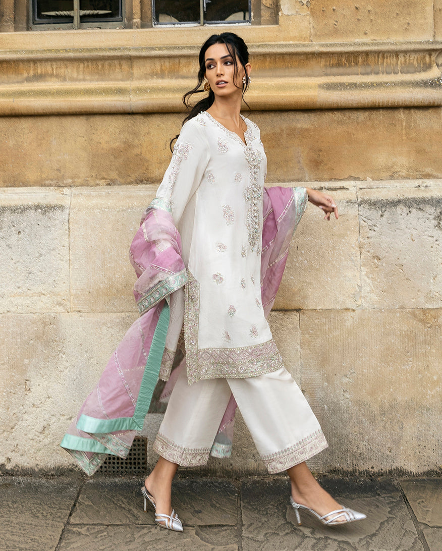 Woman wearing an Ivory Raw Silk suit, the color-blocked dupatta trailing as she walks