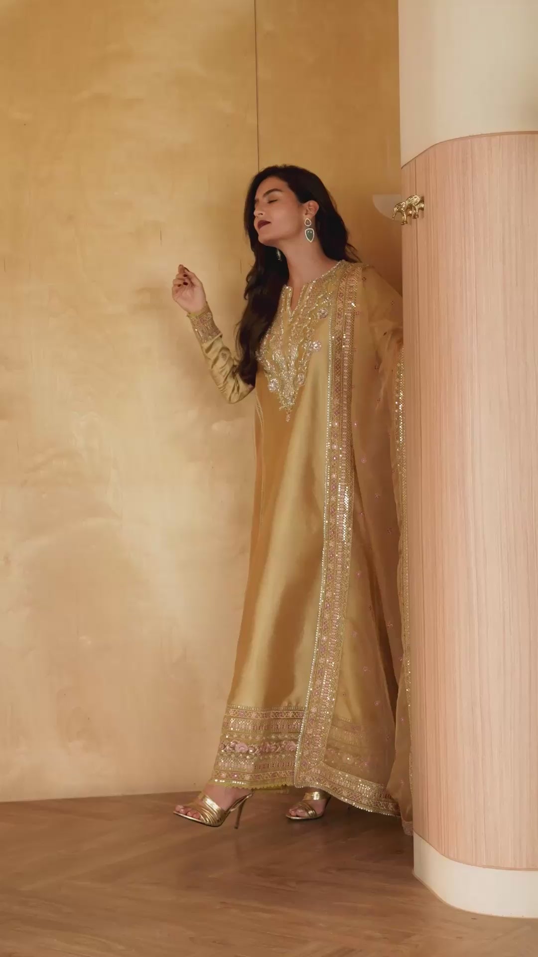 Woman wearing a golden yellow embellished kurta with sequin embroidered hem and dupatta border, browsing a clothing rack in a boutique setting, Zarminay | Luxury Pret collection
