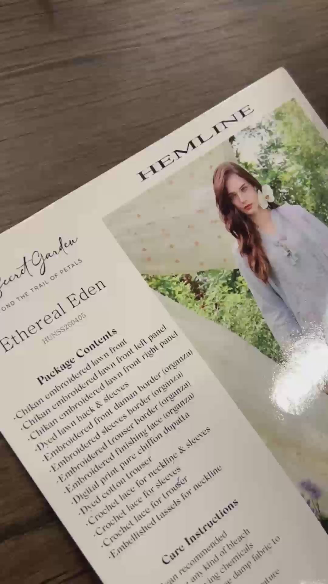 Flat-lay unboxing of light blue embroidered lawn suit fabric with lace trims, Secret Garden collection