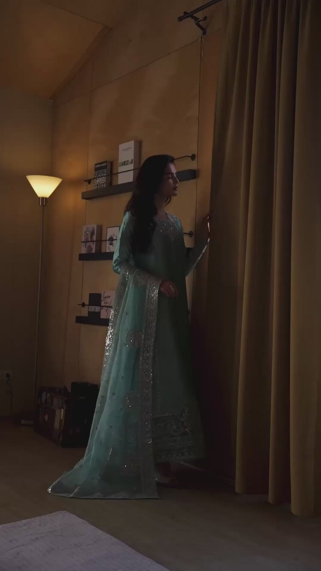 Woman wearing an aqua blue embellished kurta with silver embroidered hem and sequin dupatta, browsing a bookshelf in a styled home library, Neyla by Zarminay | Luxury Pret, Mushq.